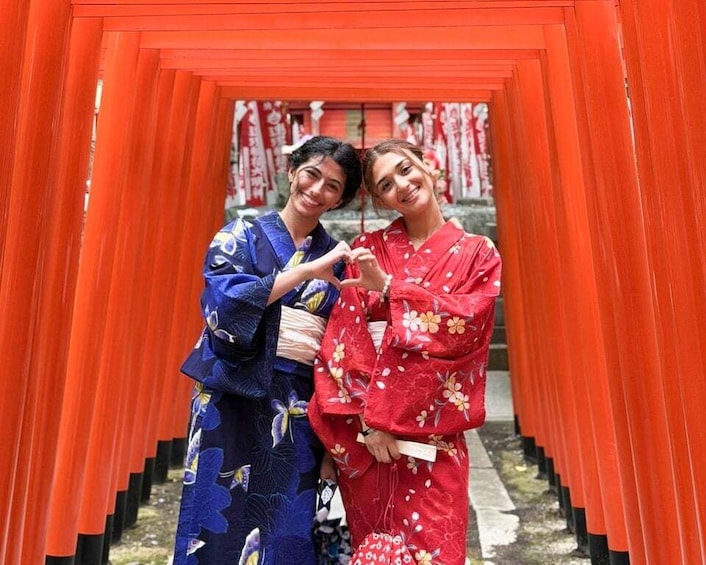 Two people in traditional Japanese attire standing in front of a red torii gate. 1