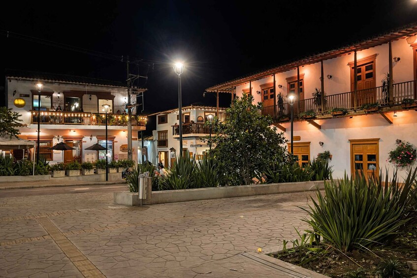 A nighttime street scene with buildings, street lamps, and outdoor seating areas. 3