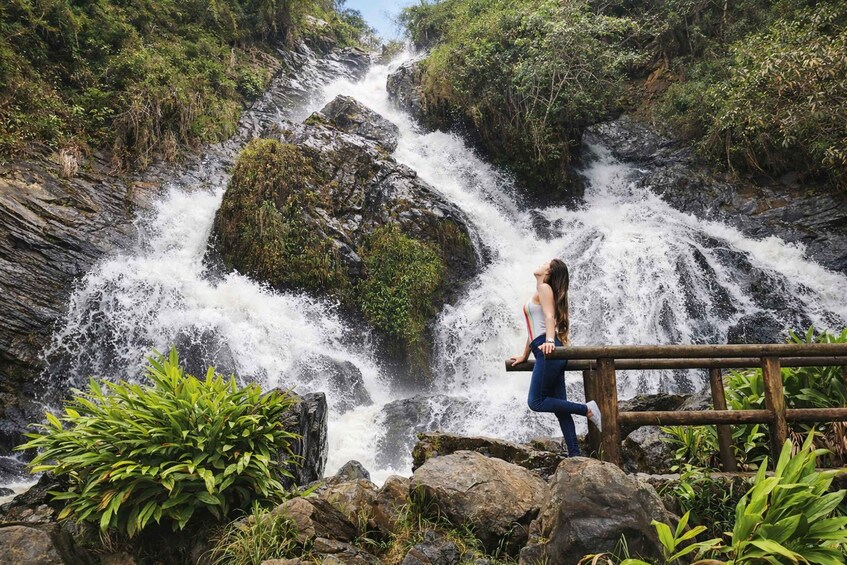 A waterfall with a person standing on a wooden platform. 1