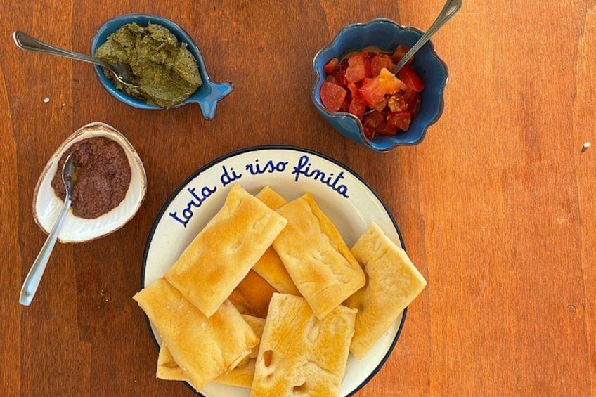 A plate of golden-brown pastries, a bowl of green sauce, and a bowl of red sauce on a wooden table. 2