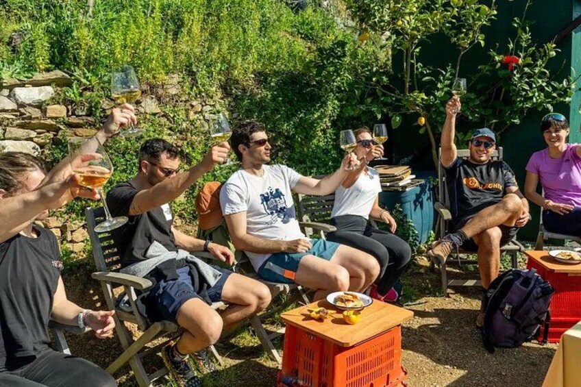 Un grupo de personas brindando con copas de vino al aire libre, rodeado de vegetación y muros de piedra. 5