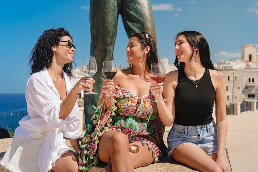 Tre persone sedute su una terrazza con una statua e uno sfondo panoramico sulla città. 5