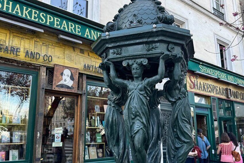 Una estatua de una mujer sosteniendo un cuenco frente a una librería llamada 'Shakespeare and Co.' 5