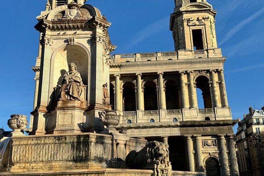 Un edificio histórico con una estatua destacada, columnas y una torre del reloj. 3
