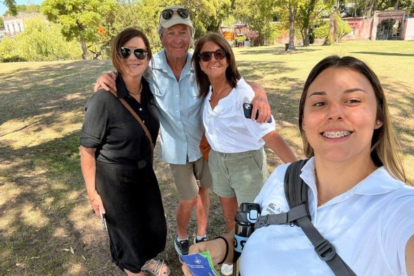 Un groupe de personnes se trouve à l’extérieur, peut-être dans un parc, avec des arbres et de l’herbe en arrière-plan. 4