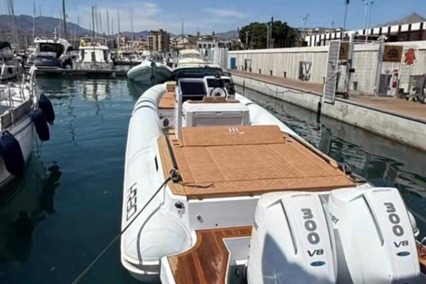 A small motorboat docked at a marina with other boats, a wooden deck, and a calm water surface. 5