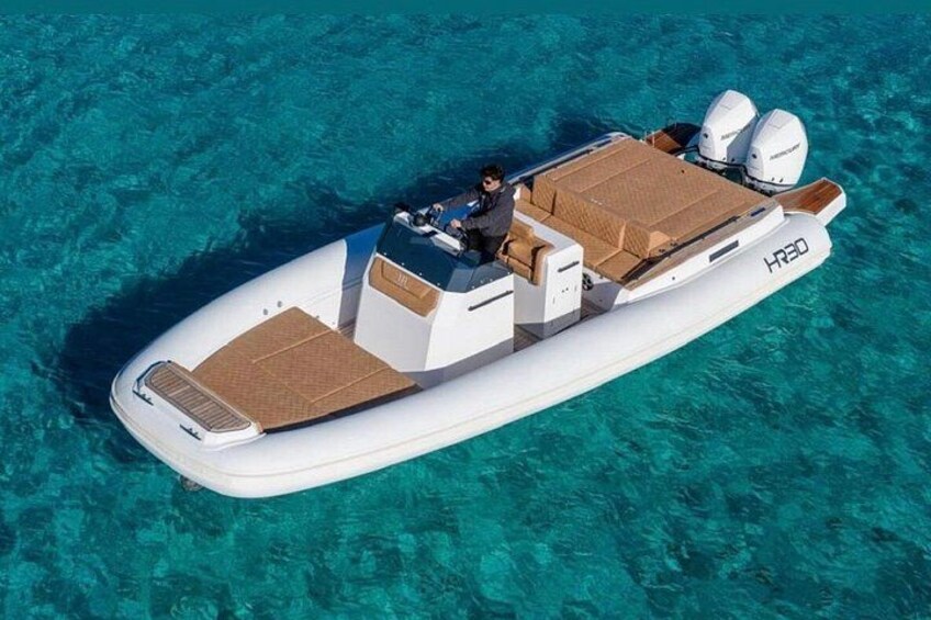 A white motorboat with a cabin and seating area on a turquoise sea. 2