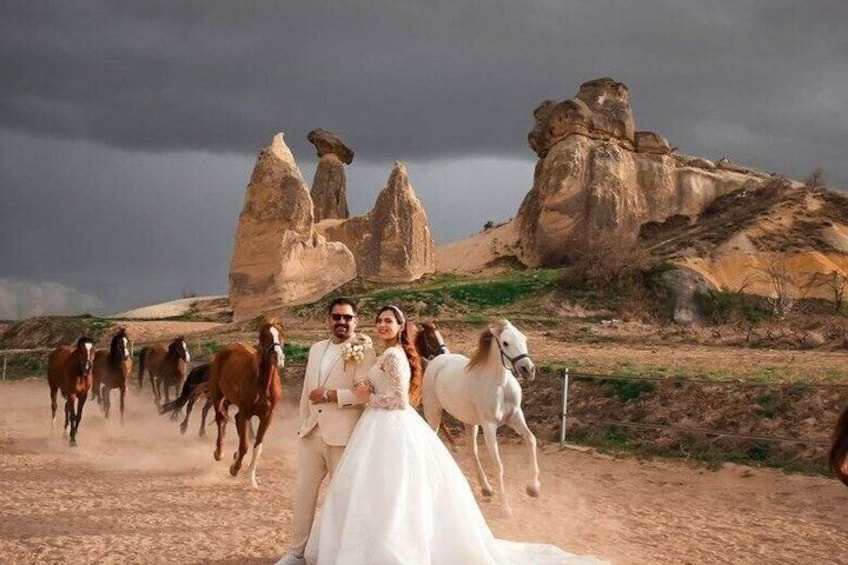 A couple in wedding attire with horses in a desert landscape with rock formations. 5