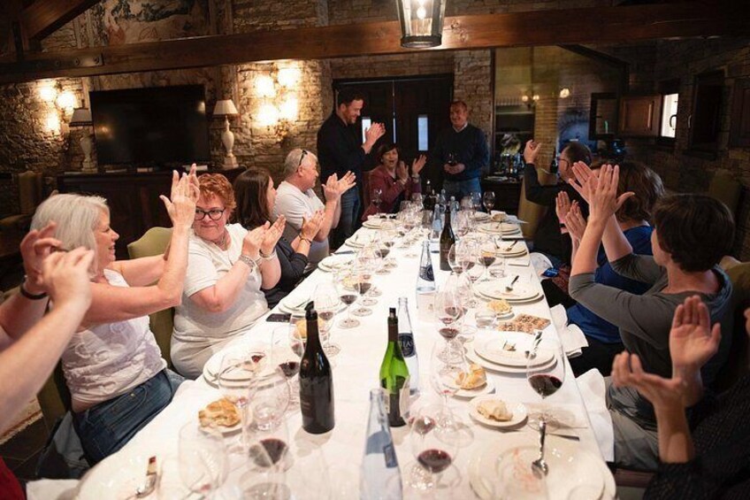 Un groupe de personnes est assis autour d’une longue table dans un restaurant et applaudit. 1