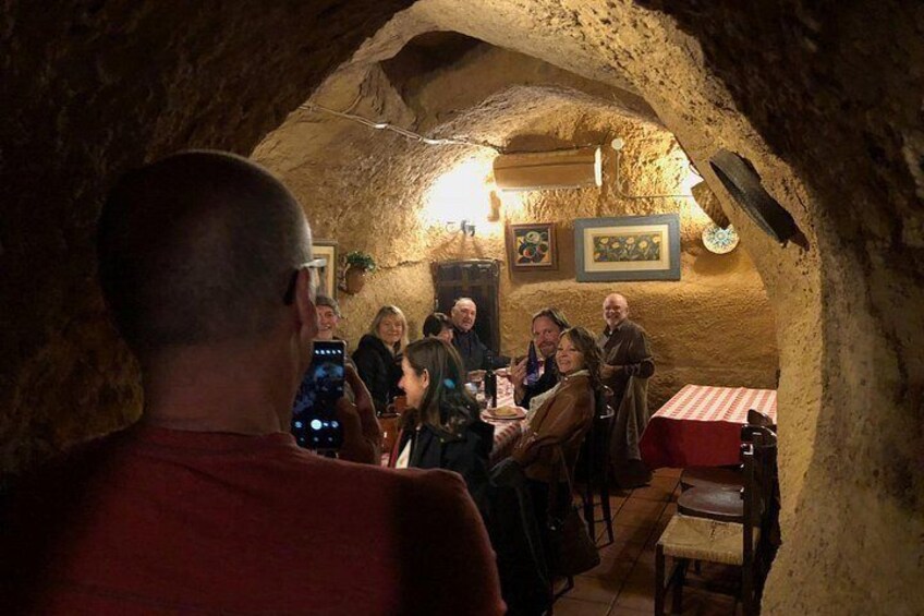 Un groupe de personnes est réuni dans un restaurant qui ressemble à une grotte, avec des murs en pierre et des meubles en bois. 4