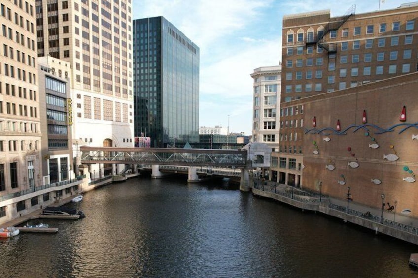 A river with a bridge, tall buildings, and a mural on a building. 1