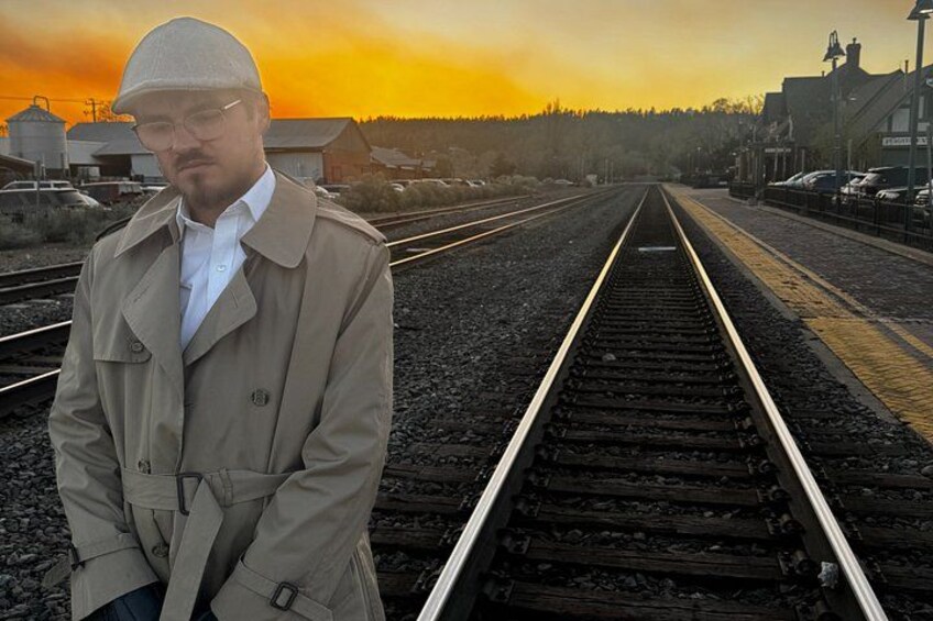 A man standing on railway tracks with a sunset in the background. 2