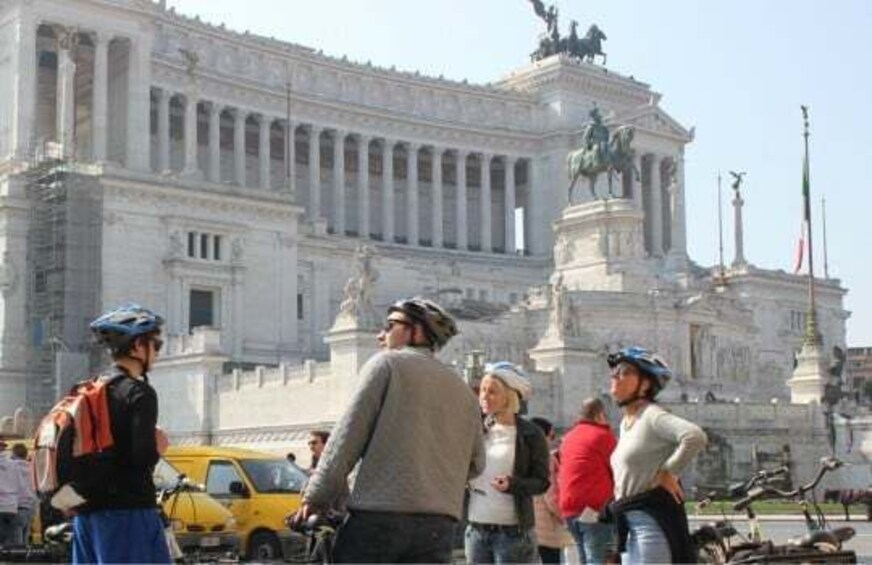 A group of people in front of a large classical building with columns and statues. 5