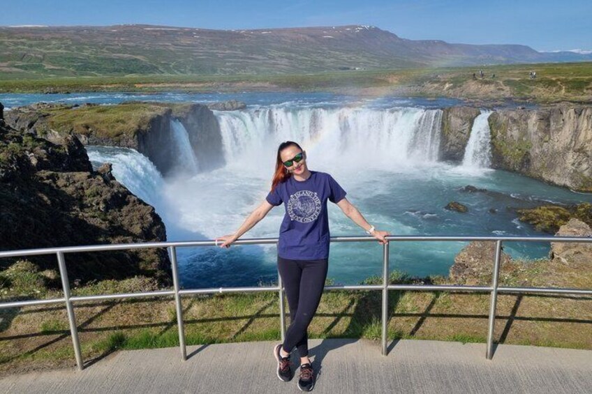 A person standing on a viewing platform with a waterfall in the background. 3