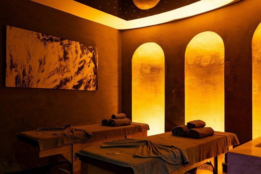 Une salle de spa équipée de tables de massage, de serviettes et ornée d’un grand tableau abstrait au mur. 1