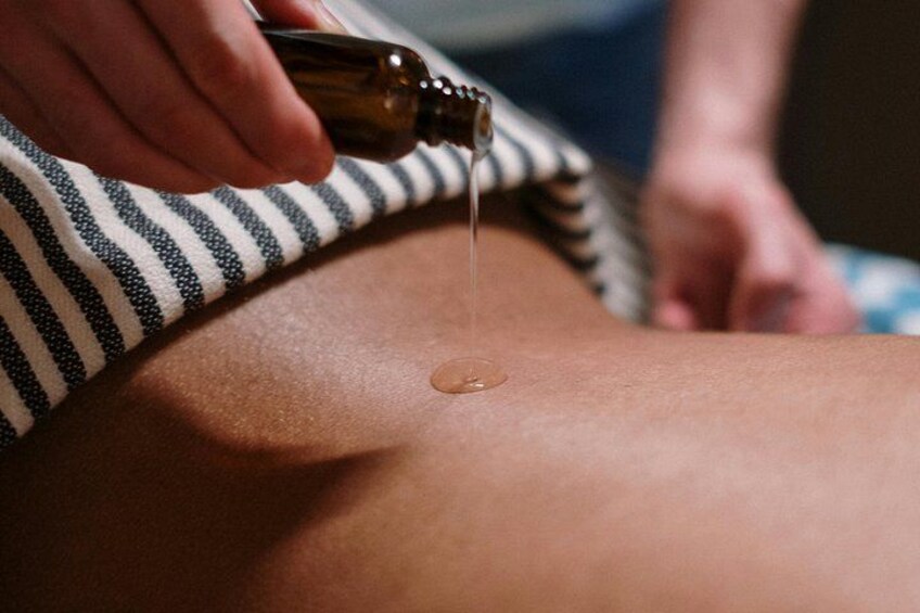 En person modtager massage, mens olie hældes over ryggen. 5