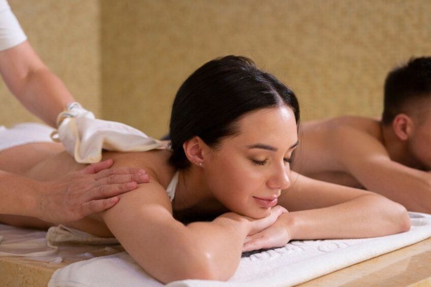 En person modtager massage, ligger på en massageloung med et håndklæde over lænden. 1