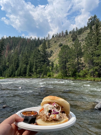 A river with a sandwich and a dipping sauce held over the water. 1