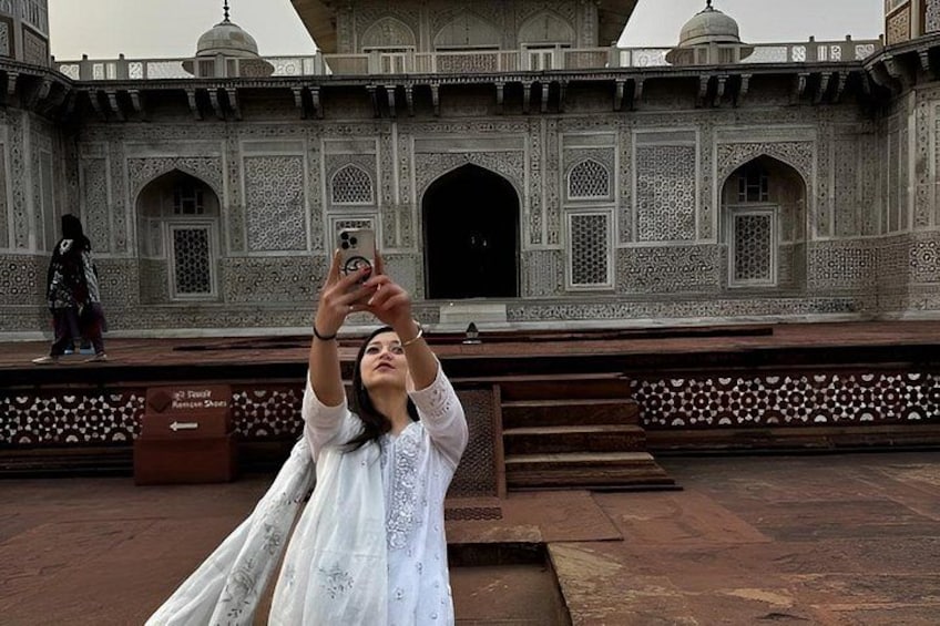 A person taking a photo with a smartphone in front of a historic building with intricate architectural details. 4