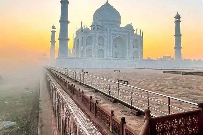 The Taj Mahal with a clear sky and a long walkway leading to it. 1