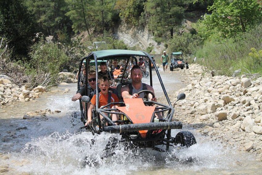 Un vehículo recorre un lecho de río pedregoso, rodeado de terreno y vegetación natural. 3