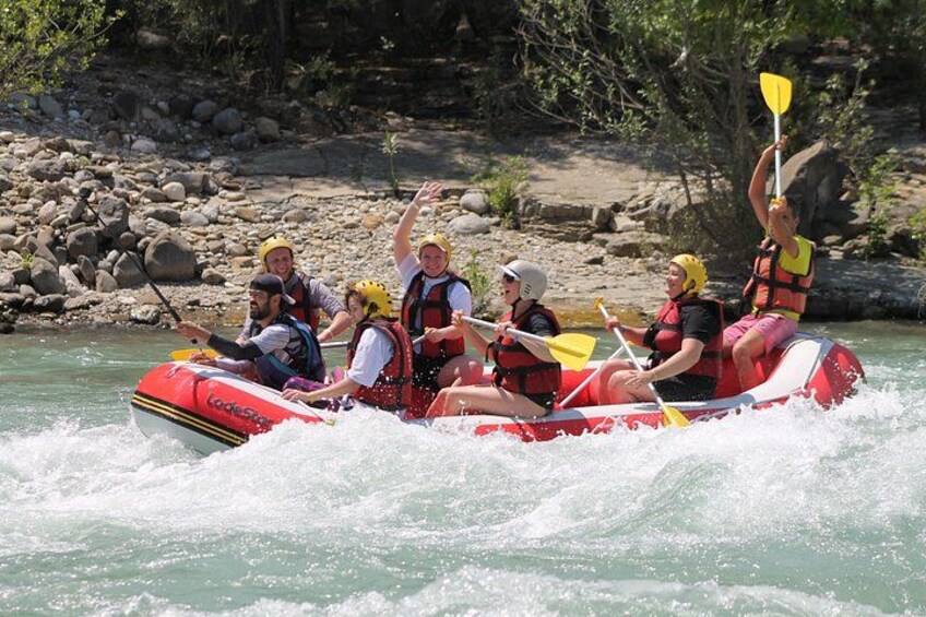 Un grupo de personas en un bote inflable rojo en un río, con chalecos salvavidas y remos. 4
