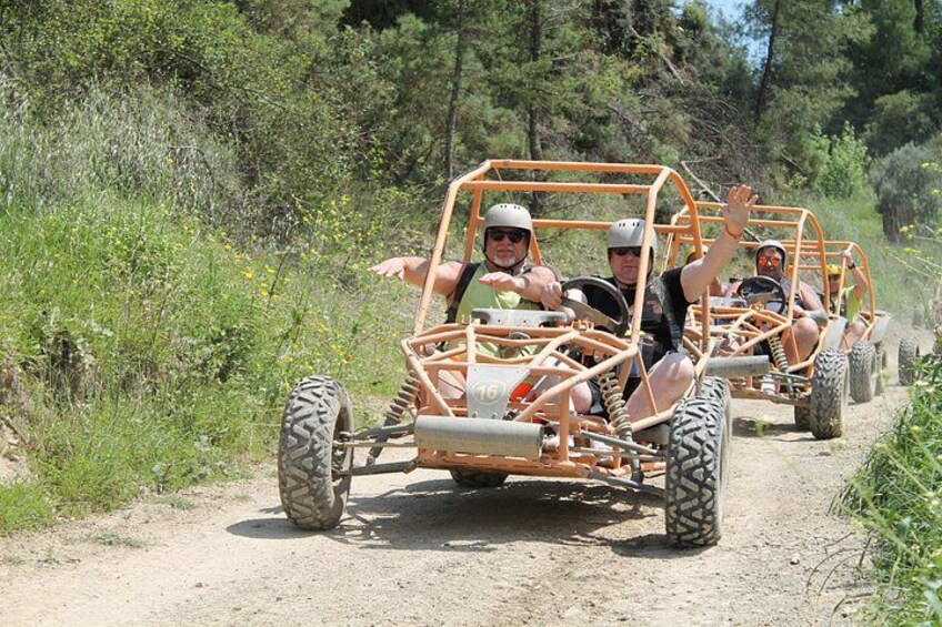 Un grupo de personas en un vehículo todoterreno naranja por un sendero de tierra rodeado de vegetación. 5