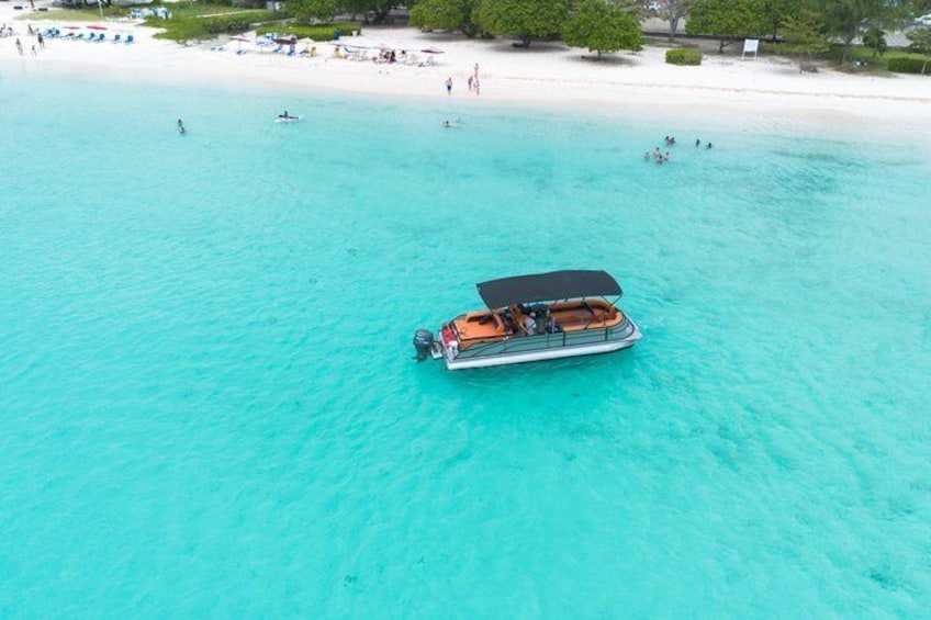 A boat on turquoise water near a beach with people and umbrellas. 4