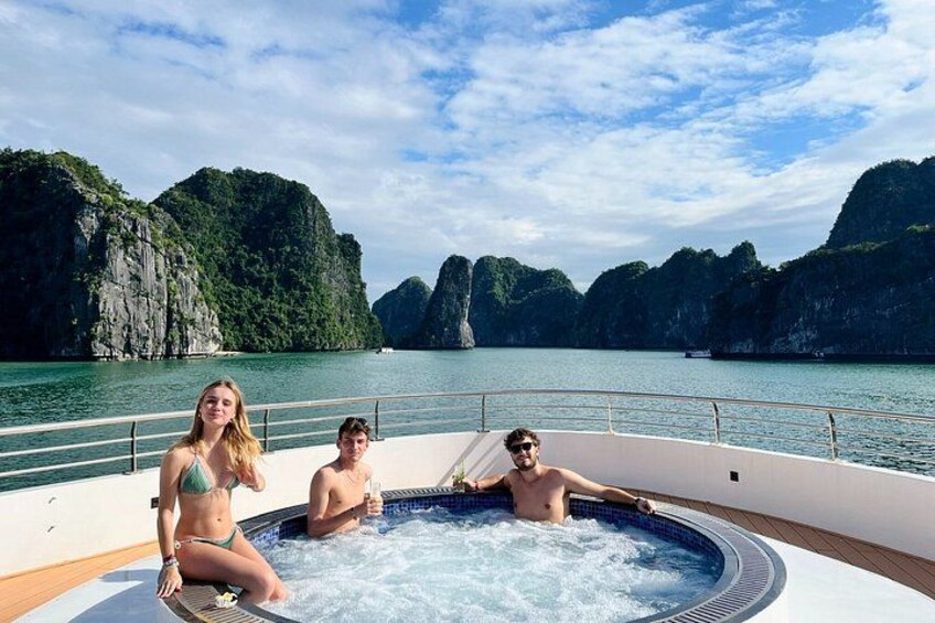 A boat with a hot tub, surrounded by water and limestone cliffs. 1