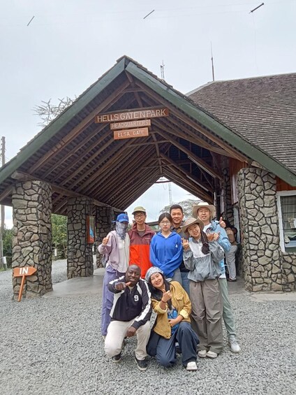 A group of people posing in front of a building labeled 'HELL'S GATE NPARK' with 'HEADQUARTERS' and 'ELSA GATE' signs. 5