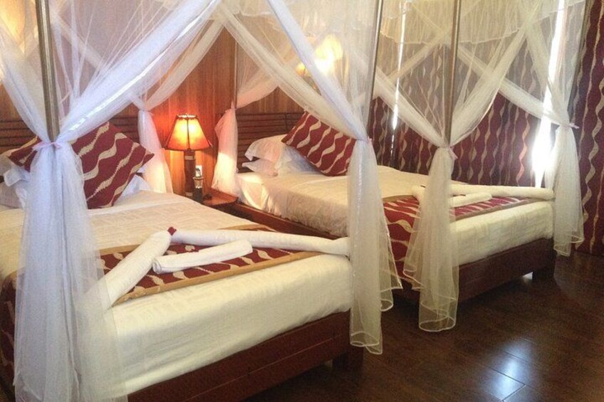 A hotel room with two beds, each with a canopy. 2