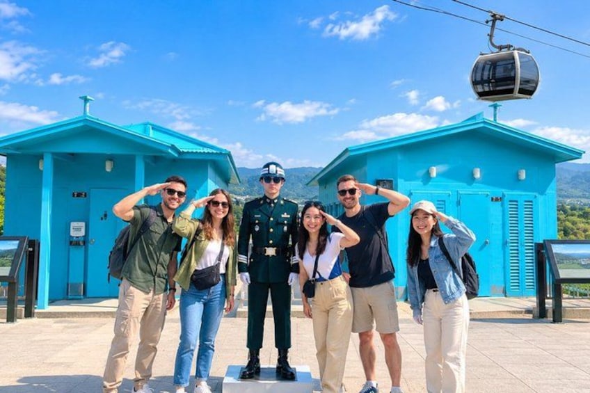 A group of people posing in front of a blue building with a cable car in the background. 3