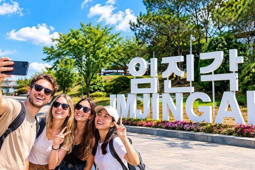 A group of people taking a selfie in front of a sign with Korean text. 1