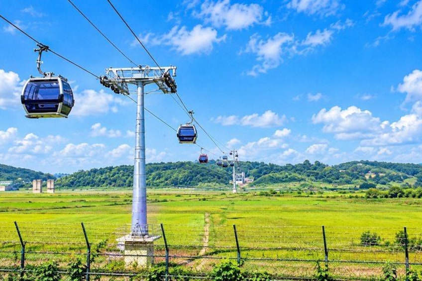 A cable car system with multiple gondolas, a metal tower, and a green landscape with hills in the background. 5