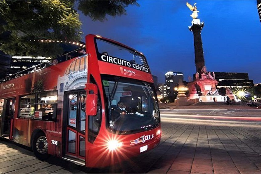 A red double-decker bus labeled 'Circuito Centro' parked on a city street at dusk. 1