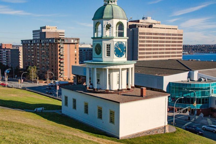 A clock tower with a dome, surrounded by modern buildings and a waterfront. 2