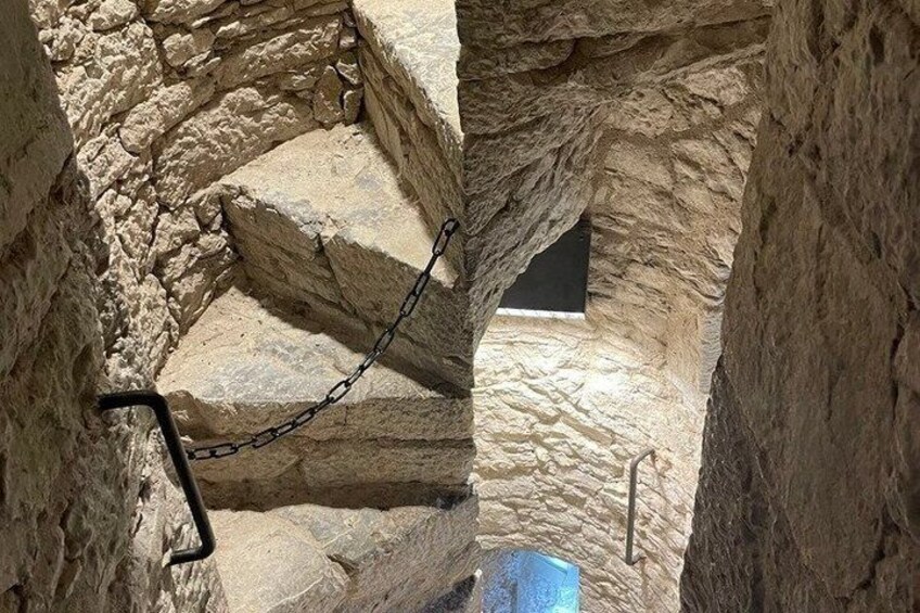 Una scala in pietra con una barriera di catena, che conduce a una piccola apertura in una struttura simile a una grotta. 5