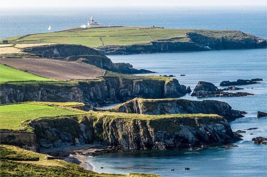 Un paisaje costero con acantilados, un faro y un velero. 4
