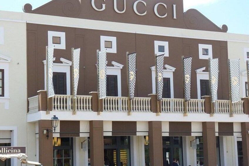 Ein Gebäude mit dem Schriftzug 'GUCCI' auf der Fassade, einem Balkon mit Geländer und einem Schild mit der Aufschrift 'Policina'. 3
