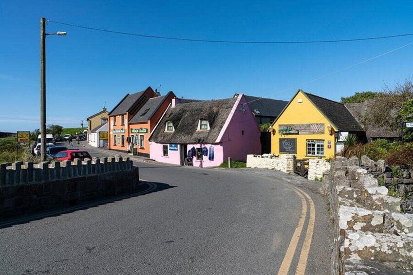 A narrow road with colorful buildings, a stone wall, and a clear blue sky. 4