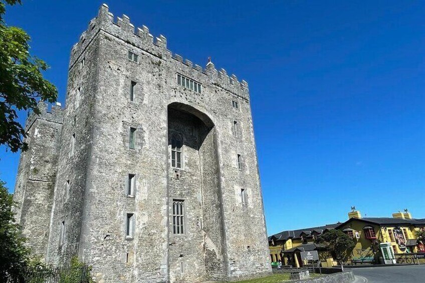 A historic stone tower with battlements, a large arched entrance, and a clear blue sky. 1