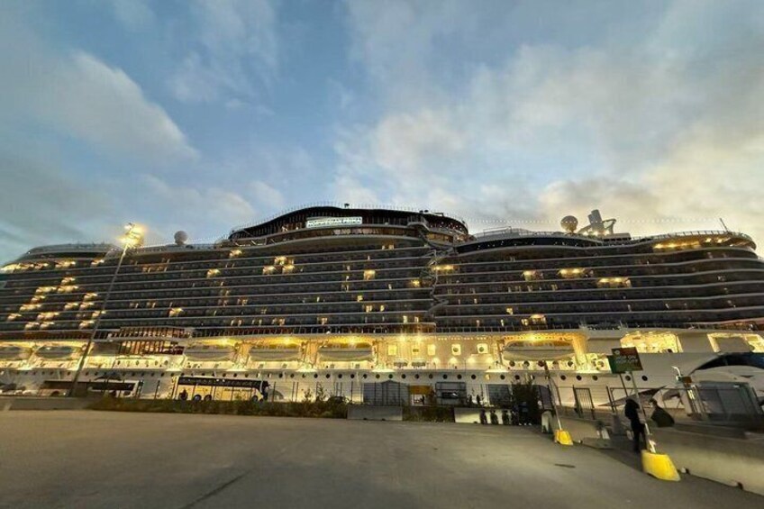 Un gran crucero amarrado en un puerto, con varios cubiertas y botes salvavidas a la vista. 2