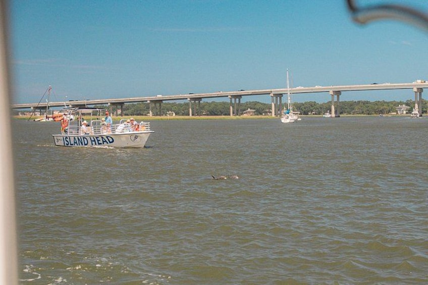 Een boot genaamd 'Island Head' op een rivier, met een brug op de achtergrond en een zeilboot verder weg. 3
