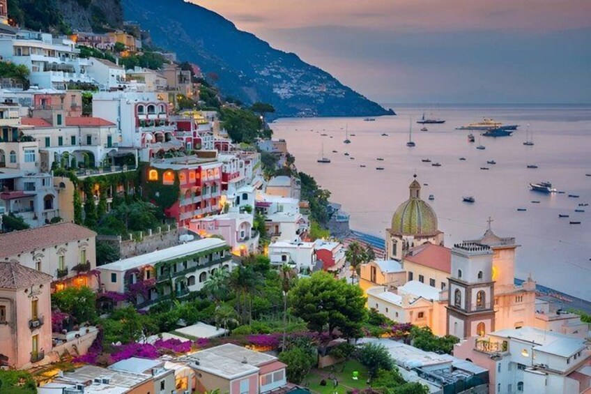 A coastal town with colorful buildings, a church with a dome, and boats in the water. 3
