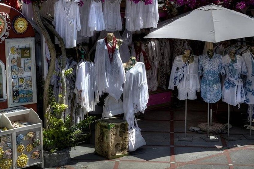 A clothing stall with white and blue garments displayed under an umbrella. 2
