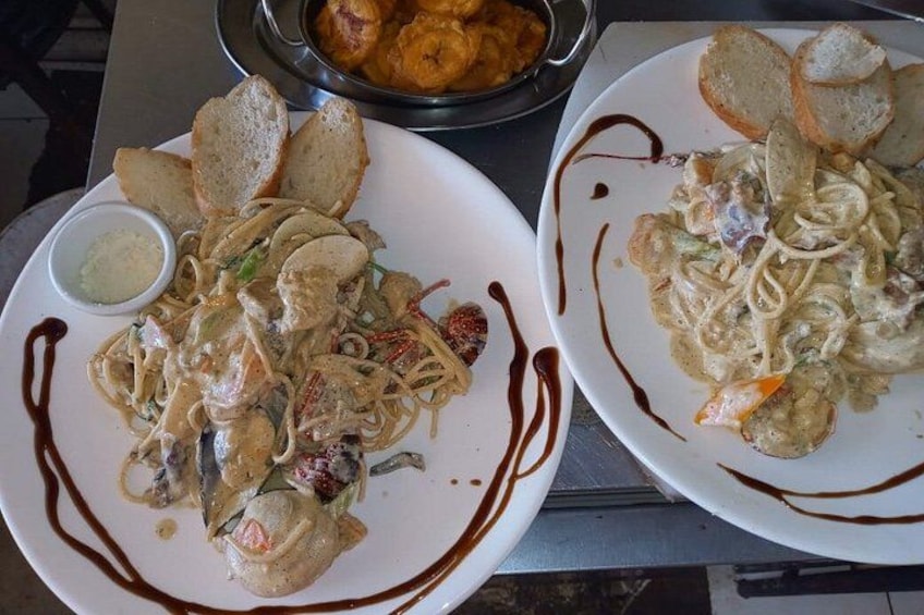 Two plates of pasta with bread and a small bowl of sauce. 2