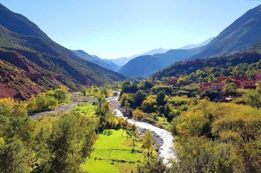 Ein Tal mit einem Fluss, grünen Feldern und Häusern am Hang. 2