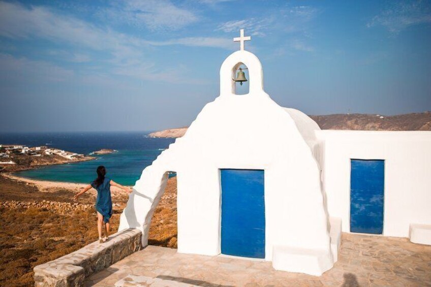 Une église blanche, dotée d’un clocher et de portes bleues, qui surplombe un paysage côtier. 3