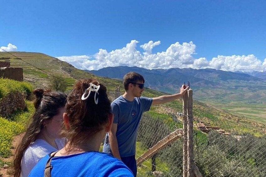 A group of people on a hill overlooking a valley with mountains in the distance. 3