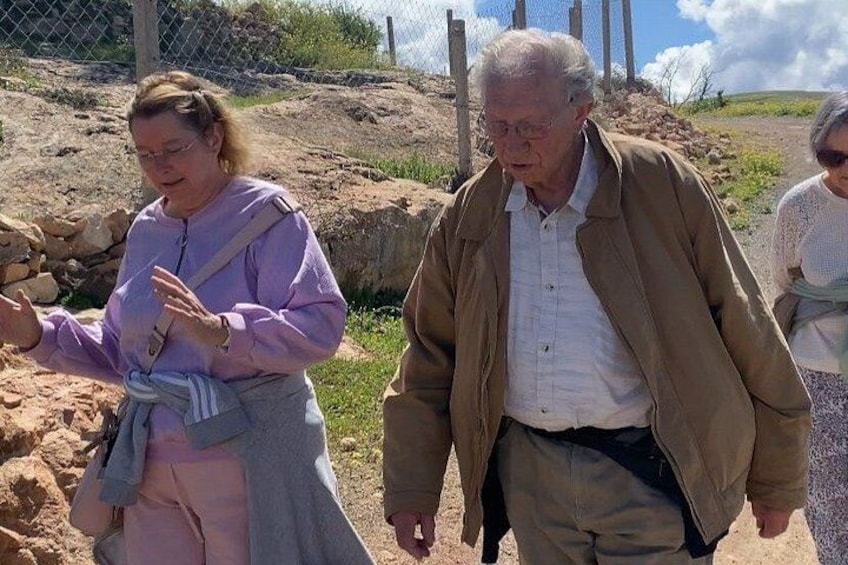 A person in a purple jacket and another in a brown jacket walking on a dirt path. 5